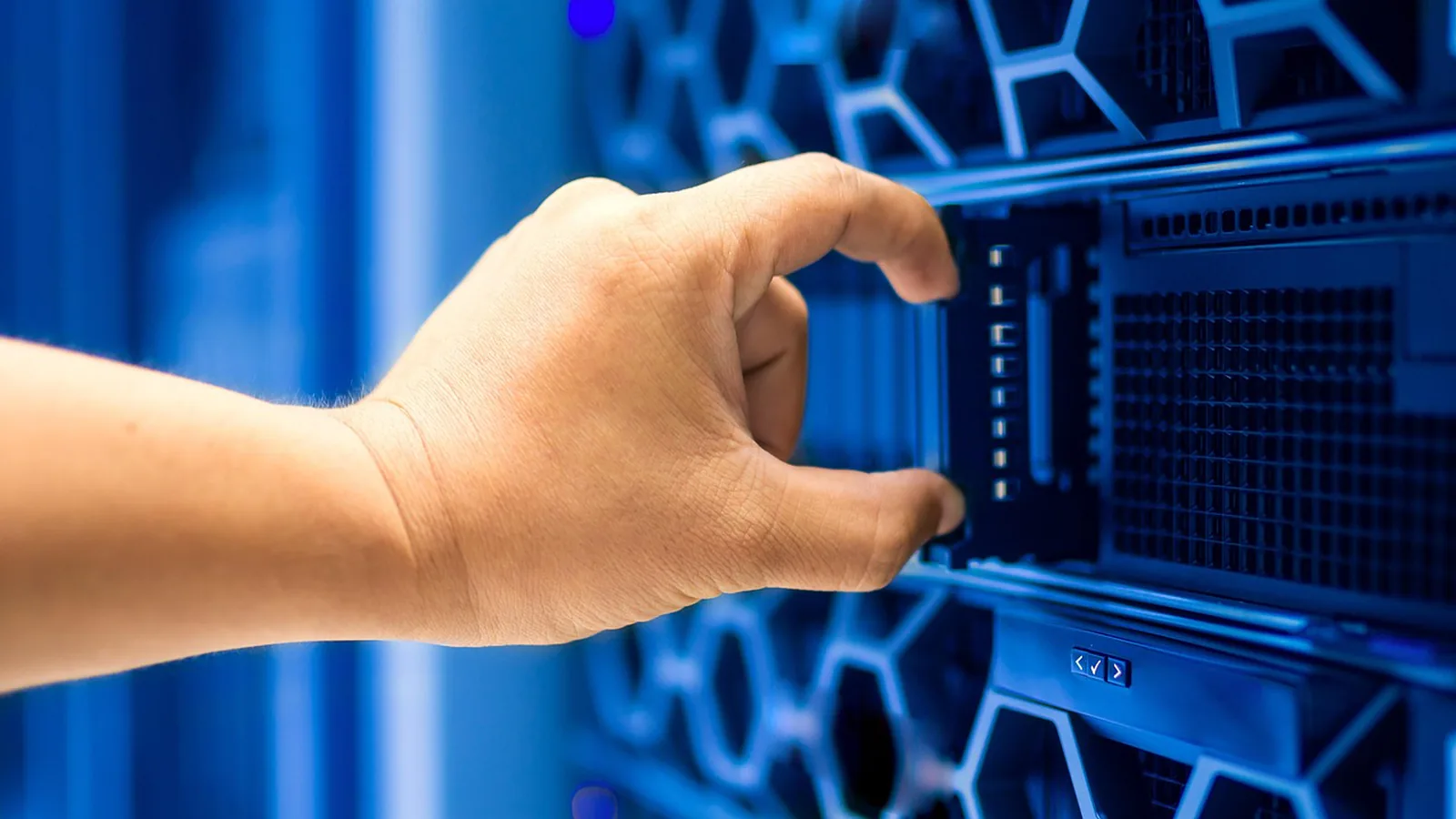 Hand pulling a server unit from a blue-lit rack, evoking the infrastructure behind a fast deployment rollback