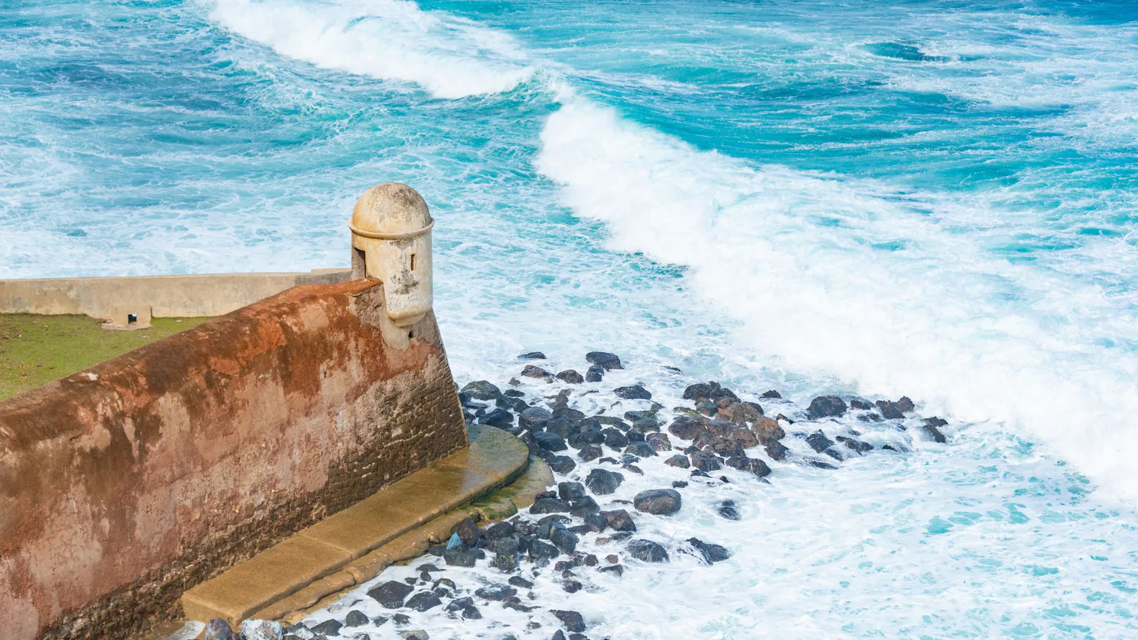 Stone sentry box on a seaside fortress wall in Puerto Rico as waves break on dark rocks below