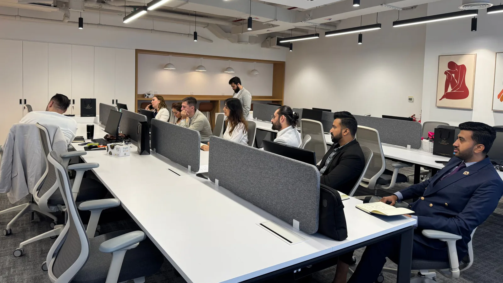 Coworking office with colleagues seated at long white desks, a setting tied to documenting where work happens
