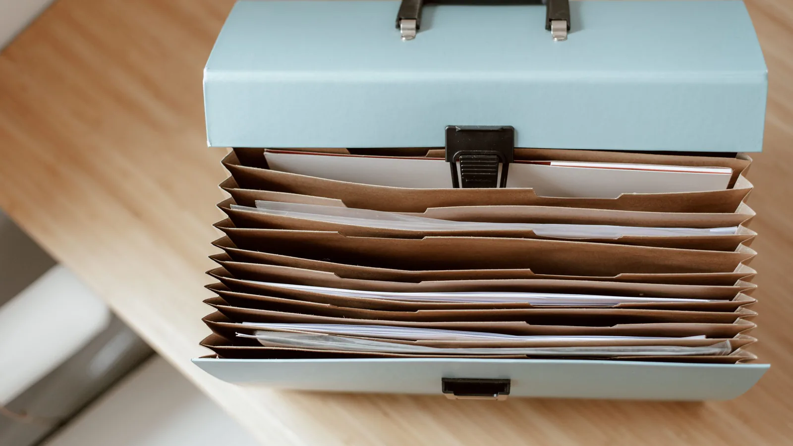 Accordion file box with papers in kraft pockets on a wooden desk, a way to sort records